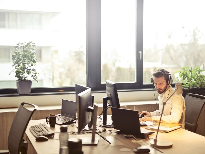 Person sitting calmly at a modern desk by a large window with plants.